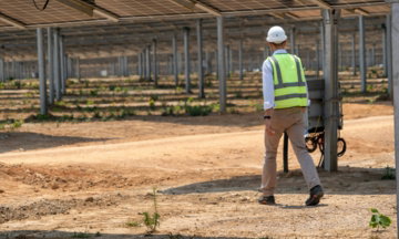A man in a hard hat and safety vest standing in a greenhouse